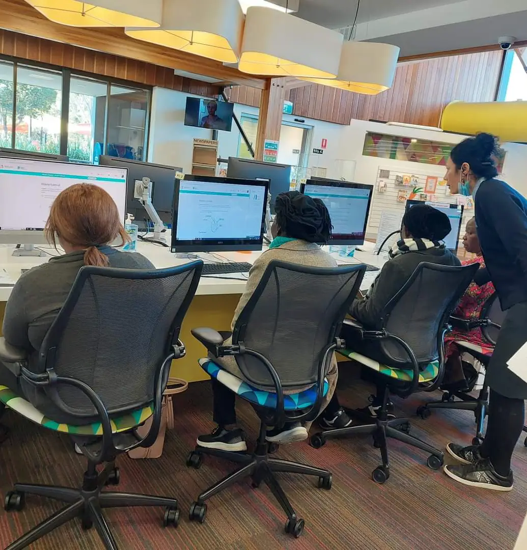 a group of people sitting in chairs in front of computers