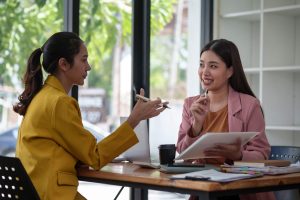 Two businesswomen discussing work at table